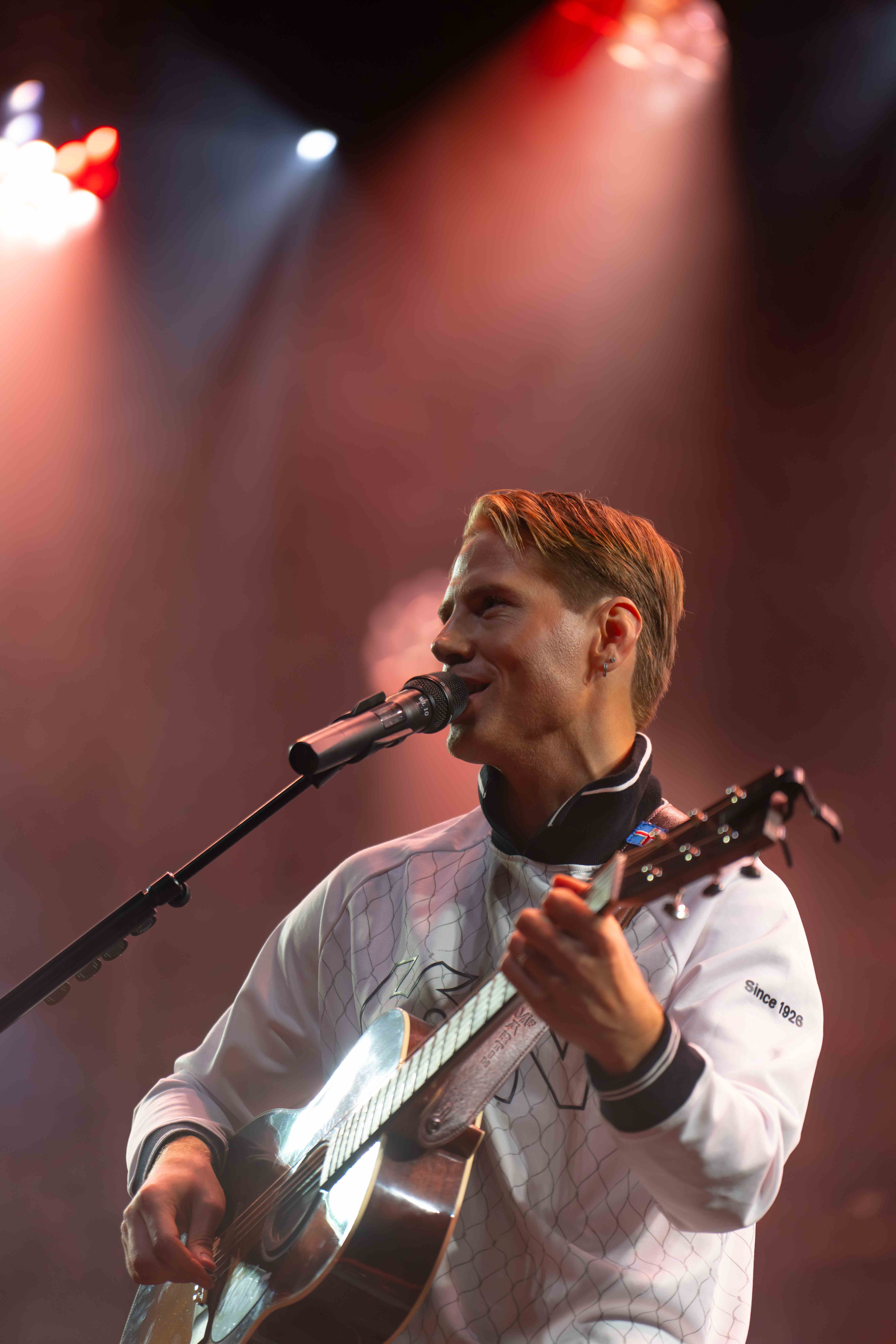 Ágúst Brynjarsson brosir við hljóðnemann á tónleikum